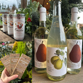 A variety of festive products displayed against a natural backdrop. Includes pear cider bottles, hot cocoa tins, and chocolate bars, evoking a warm, seasonal feel.
