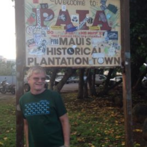 Man in a green shirt stands smiling beside a colorful 