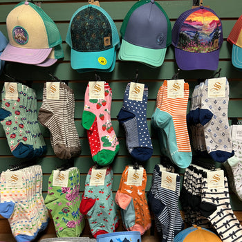 A colorful assortment of hats and socks displayed on a wall. The hats feature nature-themed designs, while the socks showcase various patterns and colors.